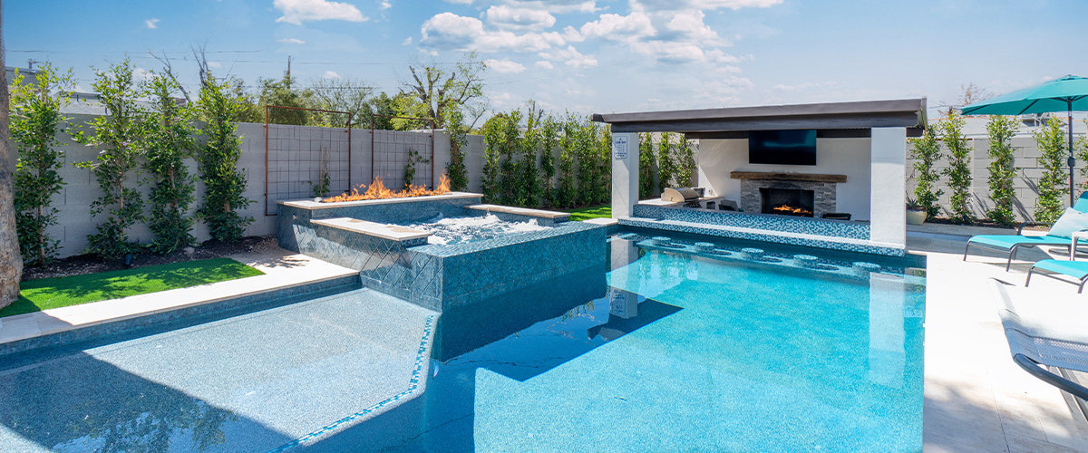 Hot tub and pool beside outdoor kitchen.