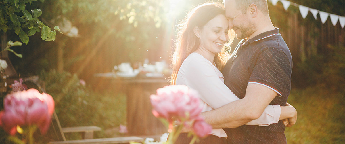Couple hugging outside with roses in background