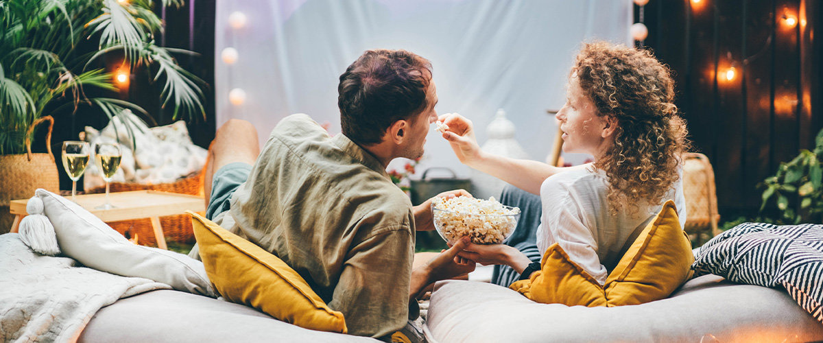 Couple feeding each other popcorn outside