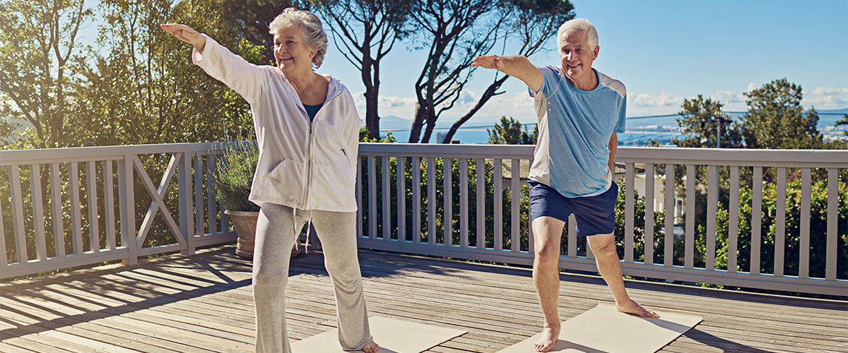 Couple doing yoga on their deck.