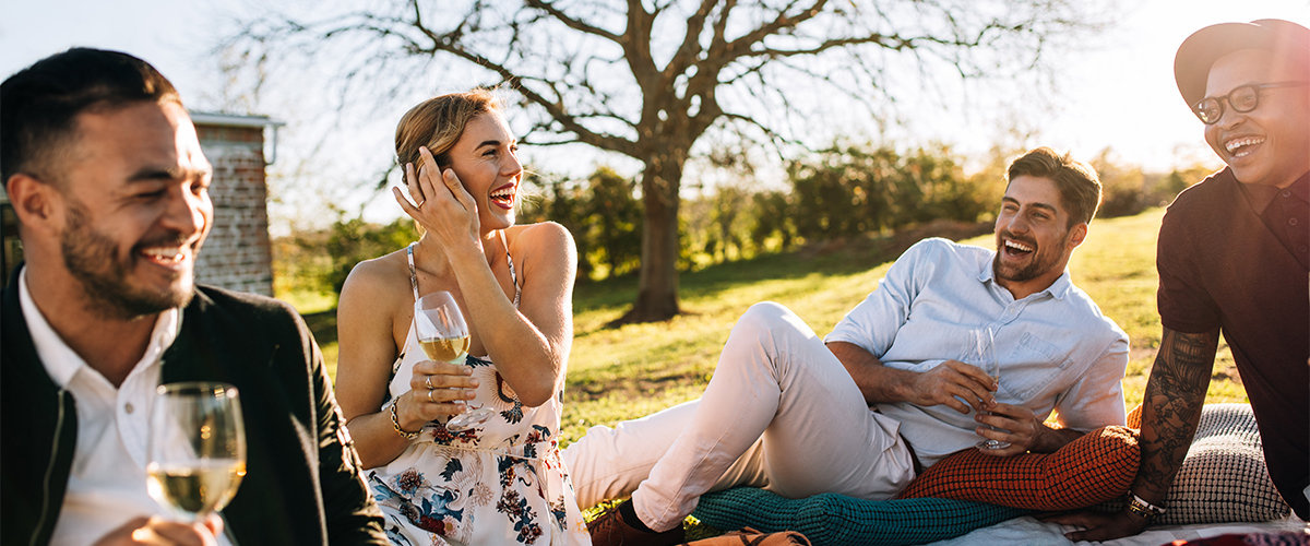 Friends laughing at backyard party sitting on pillows