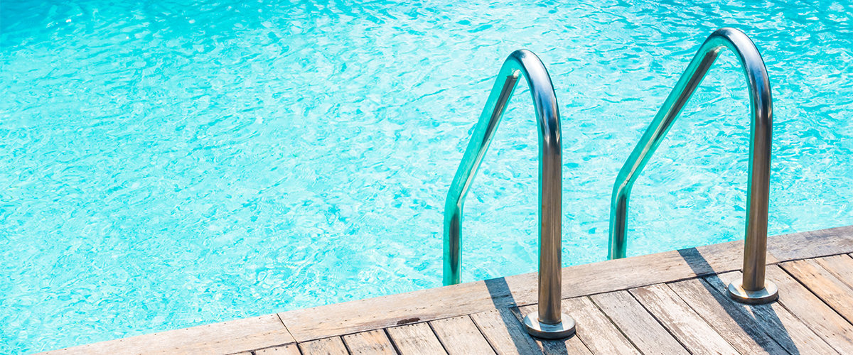 Ladder leading into backyard pool with blue water